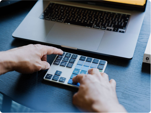 User operating the Riskeys Smart Trading Keypad alongside a laptop for efficient trading management.